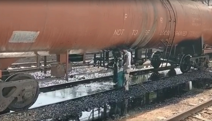 ریلوے ملازمین ٹینکر سے بہتے تیل کو روکنے کی کوشش کر رہے ہیں۔ فوٹو: اسکرین گریب