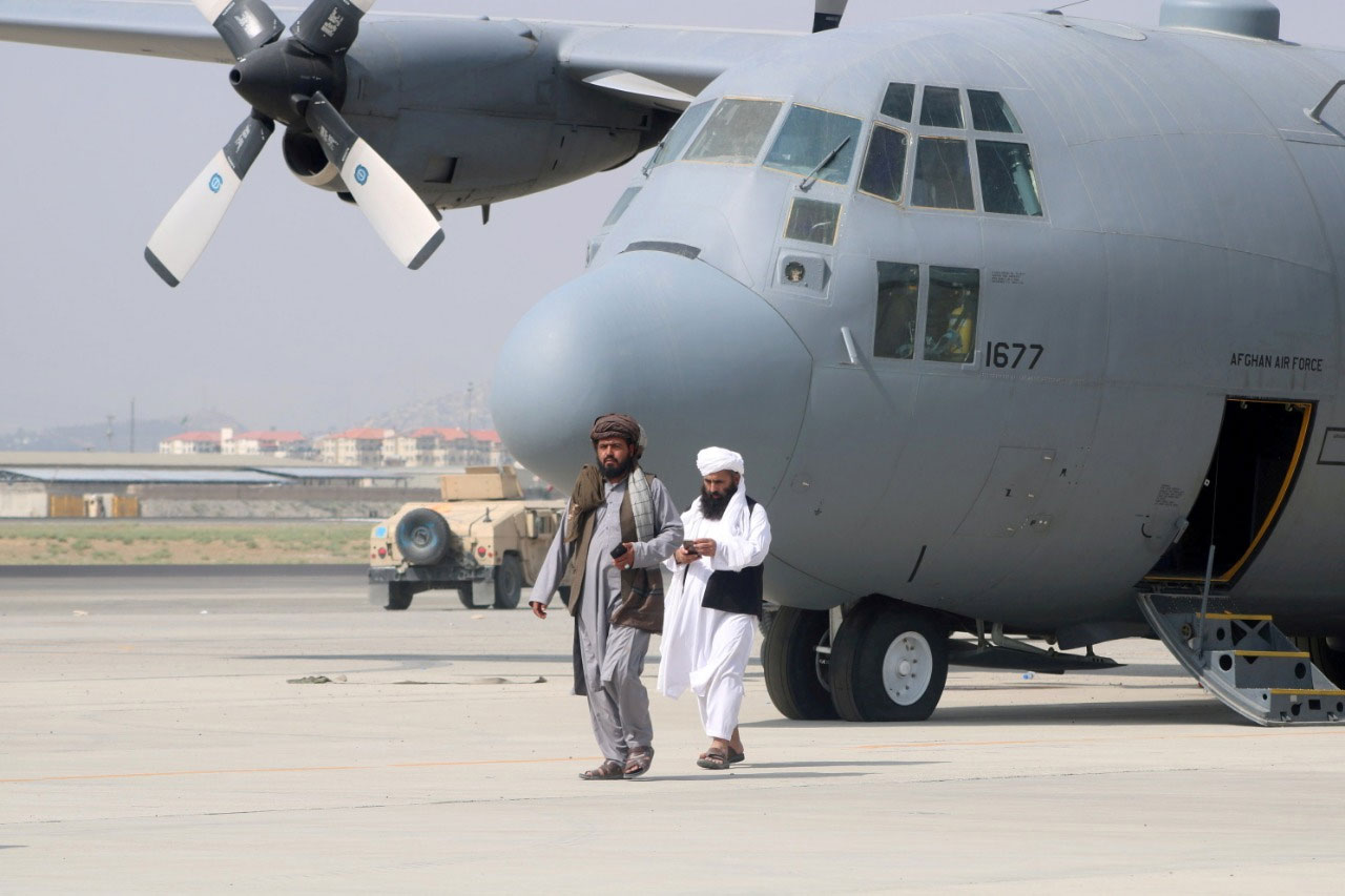 طالبان جنگجو افغان ائیرفورس کے ملٹری طیارے کے پاس موجود ہیں — فوٹو:رائٹرز