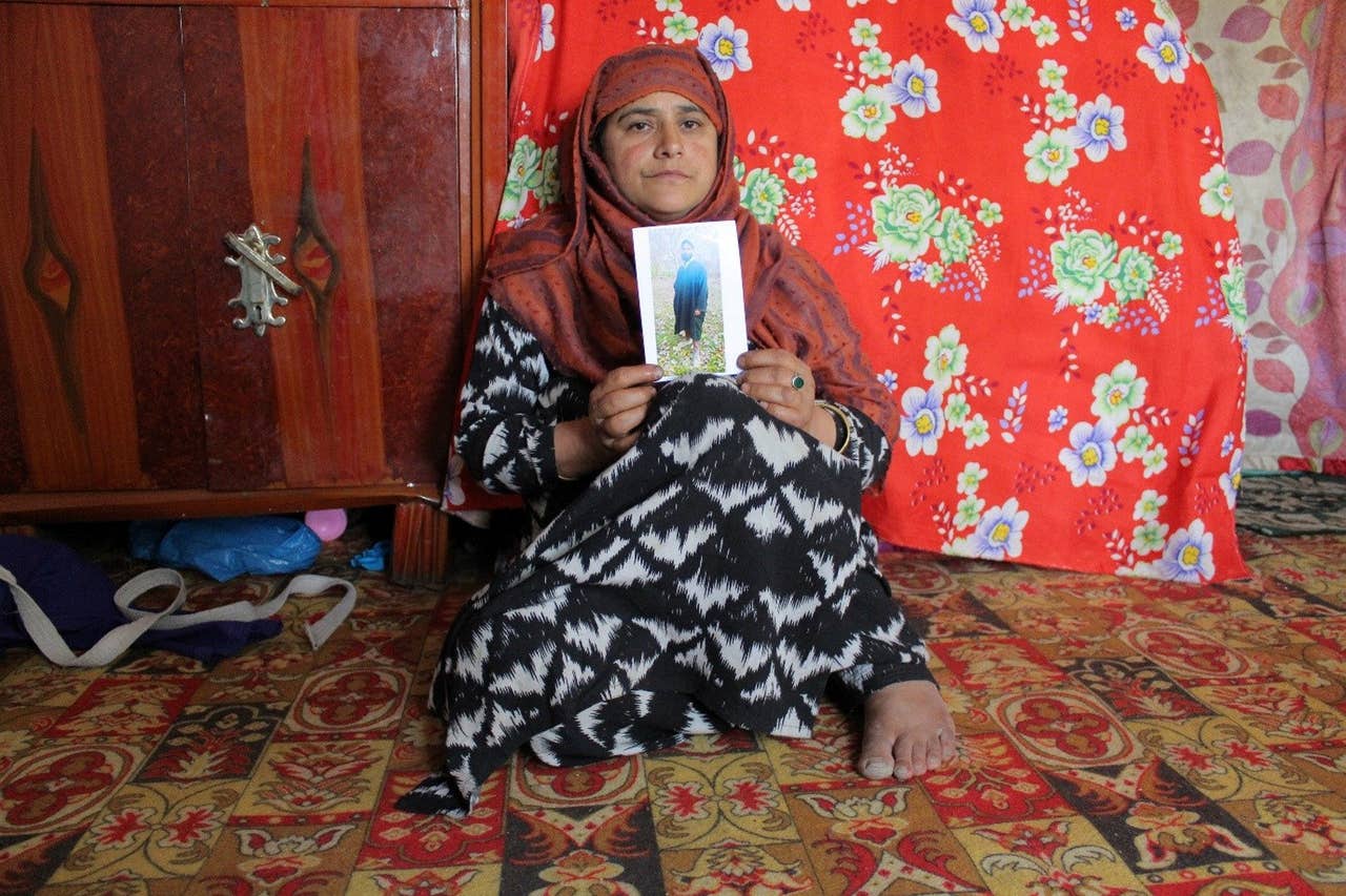 ایک کشمیری نوجوان ماجد اقبال بھٹ کی والدہ اپنے بیٹے کی تصویر لیے انتظار کر رہی ہیں، ماجد اقبال کو بھارتی فوج نے جولائی میں شہید کر دیا تھا۔ فوٹو بشکریہ ہاریٹز/عابدہ احمد